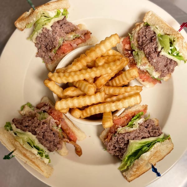 Four Hardy catering club sandwiches with corned beef, lettuce, tomato, and bacon, served with crinkle-cut fries.