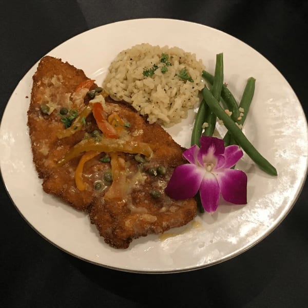 Hardy catering dish with breaded fish, rice, green beans, and a purple orchid garnish.