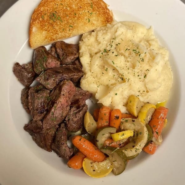 Hardy catering plate with steak bites, mashed potatoes, roasted carrots, and zucchini.